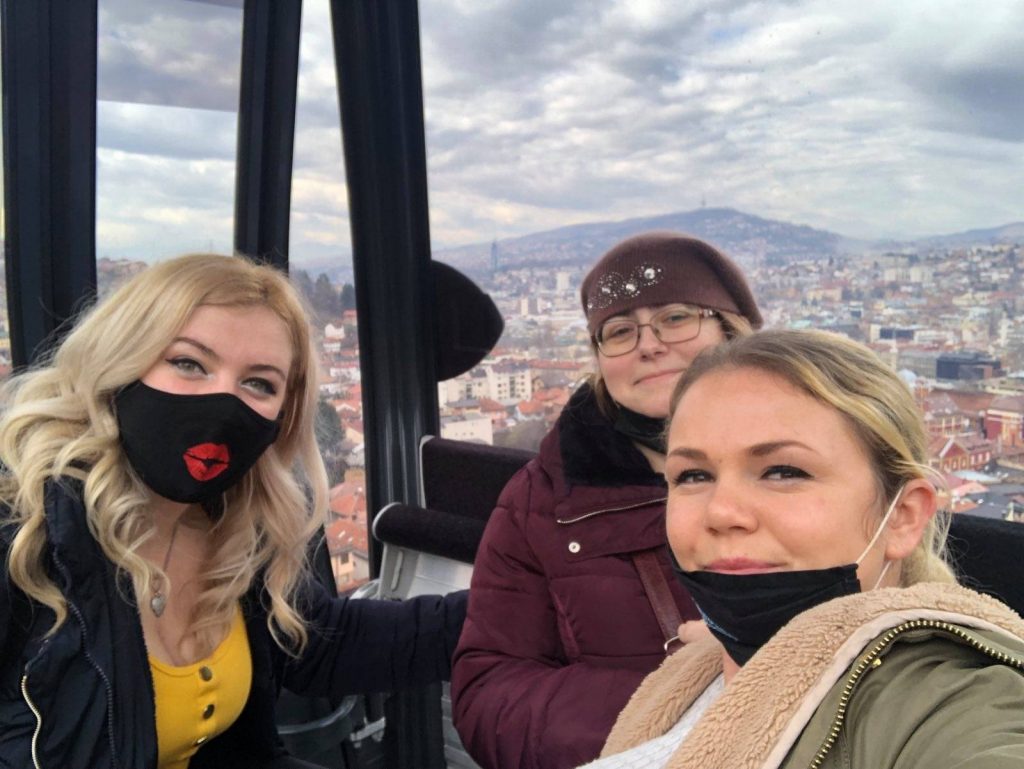 Tri žene sa zaštitnim maskama u gondoli iznad grada