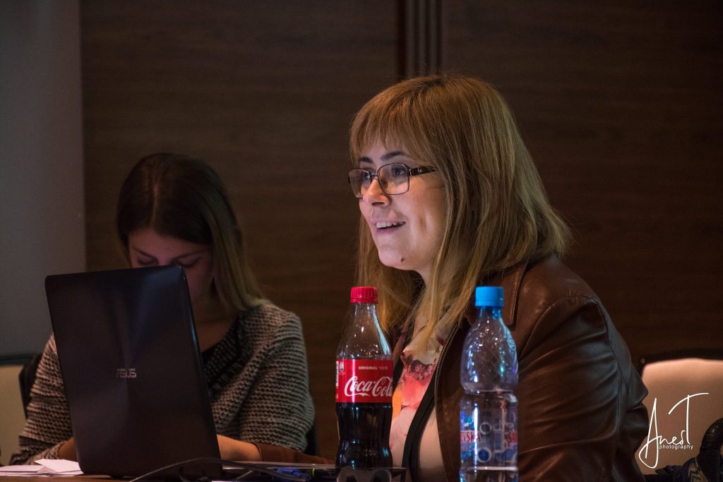 Žena s naočalama radi na laptopu za konferencijskim stolom