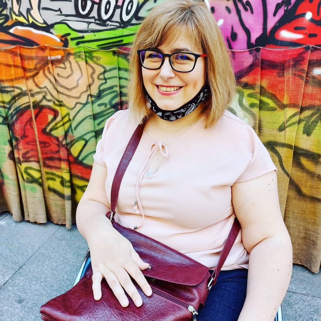 Žena s naočalama ispred šarenog grafita na zidu